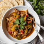 A bowl of shredded Easy Slow Cooker Chicken Fajitas with colorful bell peppers and onions.