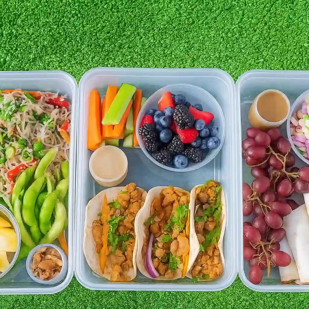 Woman packing vegan meal prep recipes bowls with high-protein ingredients like quinoa, tofu, and roasted sweet potatoes