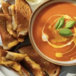 Bowl of Roasted Pumpkin and Tomato Soup garnished with herbs and drizzled with olive oil.