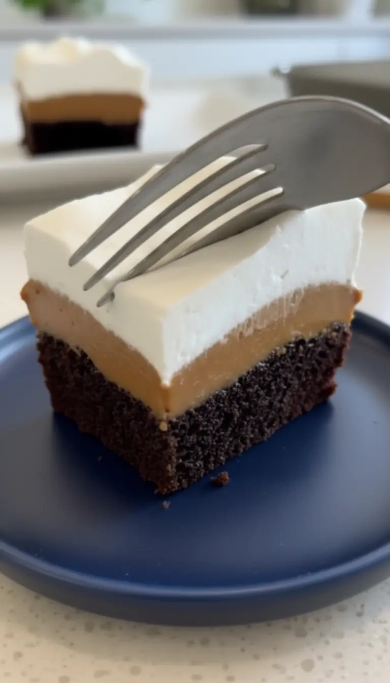 Easy 4-Ingredient Peanut Butter Chocolate A top-down view of baking ingredients arranged on a light wooden table, including flour, cocoa powder, sugar, eggs, milk, and a can of dulce de leche, with a finished slice of 3-layer chocolate cake on a blue plate in the background.