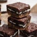 A close-up stack of three layered slutty brownies showing chocolate chip cookie, Oreo, and fudge brownie layers, perfectly baked for those wondering how long to cook slutty brownies