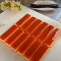 Close up of perfectly sliced rectangular Vanilla Caramel Custard Tart portions arranged on a white surface.