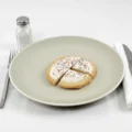 A frosted sugar cookie with colorful sprinkles cut into four pieces on a light plate, a helpful visual for understanding portion size and sugar cookie nutritional value.