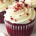 A close-up of a frosted red velvet cupcake sprinkled with red crumb garnish, a classic dessert option alongside red velvet brownies.
