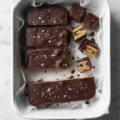 Top-down view of homemade chocolate-covered wafer bars sprinkled with flaky sea salt in a white baking dish, perfect for easy gluten free desserts.