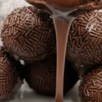 A close-up of gooey Quick Chocolate Brownie Truffles covered in chocolate sprinkles with rich melted chocolate pouring over the top.