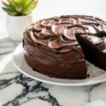 how to make a chocolate fudge cake step by step served on a marble board with fresh garnish